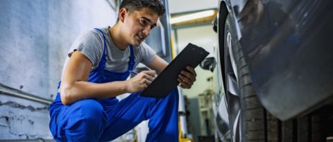 Person with a clipboard inspecting a GM vehicle's tires.