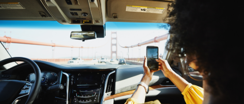 Mujer fotografiando el puente Golden Gate desde el asiento del pasajero del automóvil